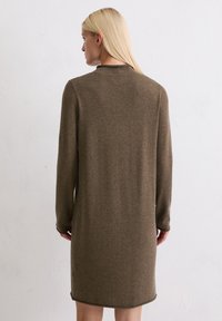Braunes Strickkleid mit langen Ärmeln, hohem Ausschnitt und geradem Schnitt. Verfügt über einen abgerundeten Saum und ein minimalistisches Design.