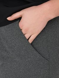 Hand gedeeltelijk in de voorzak van grijze, gestructureerde broek, gekleed in een zwart topje.