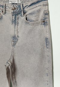 Vaaleat farkut, joissa on etutasku, metallinen nappi ja näkyvä Stradivarius-logokohta vyötäröllä.