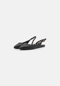 Melnas slingback balerīnas ar norādītu purngalu, izgatavotas no gludas ādas, ar zeltainiem kniedēm un siksniņu ar sprādzi, lai pielāgotu izmēru.