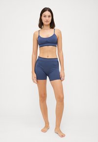 Navy blue athletic bralette with thin straps and tonal texture, paired with matching fitted shorts with a high waistband.