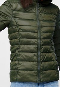 Doudoune olive verte avec un motif de matelassage horizontal, fermeture éclair et capuche. Fabriquée en matériau léger et brillant.