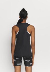 Černé bezrukávové sportovní tílko s kulatým výstřihem, hladkou texturou, v kombinaci s černými šortkami s opakujícím se bílým vzorem loga.