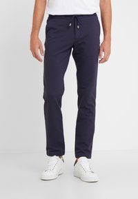 Marineblå joggerbukser med elastisk talje og justerbar snor, lavet af blødt materiale, med sidelommer og en slim fit-design.