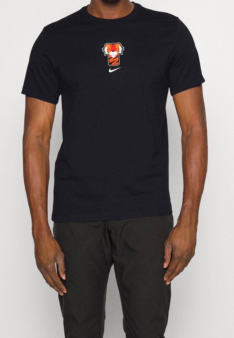 Svart bomulls t-shirt med en grafisk design av en orange och vit tiger samt en liten vit Nike-logotyp på framsidan. Korta ärmar.
