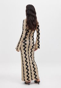 Pikkade varrukatega beezist kootud kleit, millel on liibuva lõikega disain ja julged mustad lainelised triibud. Sile tekstuur flokeeritud varrukatega ja põrandani ulatuv hem.