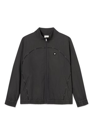 Giacca nera leggera con zip, polsini elastici, tasche laterali e un piccolo emblema bianco sul petto sinistro.