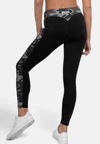 Schwarze Leggings mit einem grauen Camouflage-Muster am Bund und an der Seite. Hergestellt aus dehnbarem Material für Komfort. Verfügt über ein eng anliegendes Design.