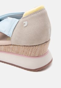 Béžová klinová sandála s svetlomodrým remienkom, tkanou strednou podrážkou, žltým polstrovaním päty a bielou gumovou podrážkou s ružovými akcentmi.