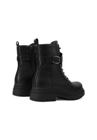 Stivali alla caviglia in pelle nera con lacci frontali, zip laterale e una fascia con cinturino. Presentano una suola spessa e una texture liscia.