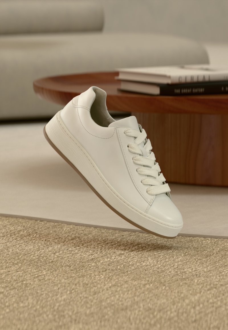 Λευκό δερμάτινο αθλητικό παπούτσι με λεία υφή, στρογγυλεμένη μύτη και λευκά κορδόνια. Διαθέτει ανθεκτική ελαστική σόλα με οριζόντιες αυλακώσεις.