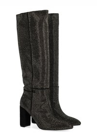 Bottes noires arrivant au genou avec une surface texturée de petits clous métalliques, bout pointu et talon épais. Accentuation avec un liseré noir lisse.