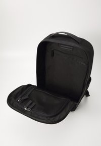Black backpack made of durable fabric; features a main compartment, front zip pocket, mesh organizer, and a top handle for carrying.