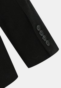 Manche d'une veste noire en tissu doux, de forme ajustée, avec quatre boutons noirs au poignet.