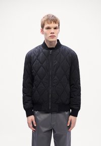 Μαύρο τυπωμένο μπόμβερ μπουφάν με φερμ�ουάρ μπροστά, ριμπ μανίκια και γιακά. Διαθέτει διαμαντένιο μοτίβο και ελαφρύ υλικό.