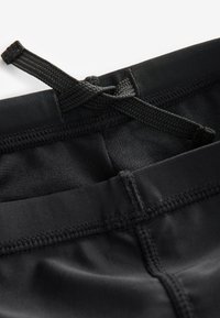 Shorts de bain noirs avec une taille texturée et un cordon de serrage intégré. Comprend des coutures à plat pour le confort et le soutien.