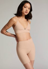 Naadloze bralette en shorts in huidskleur, met een gladde textuur en minimalistisch ontwerp met dunne bandjes.