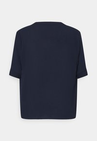 Top blu navy a maniche corte con una vestibilità morbida, caratterizzato da un collo rotondo e maniche arrotolate, realizzato in un tessuto liscio.