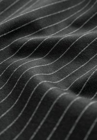Schwarzer Stoff mit feinen weißen Nadelstreifen, der eine weiche Textur und einen leichten Glanz aufweist, was ein wellenartiges Muster durch das Drapieren erzeugt.