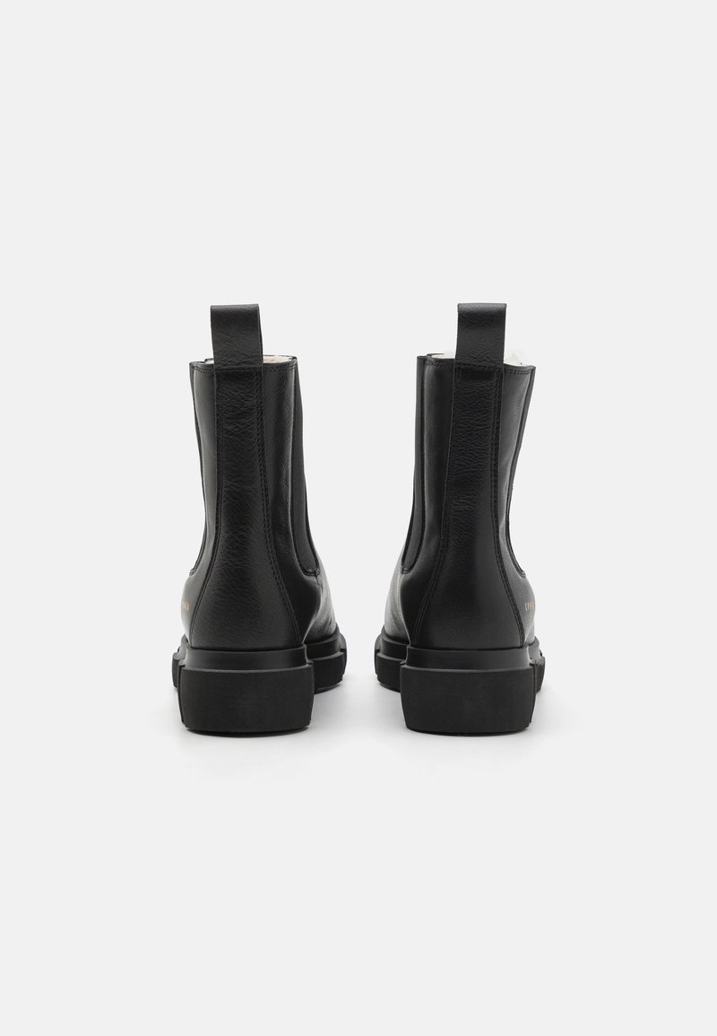 Schwarze Leder-Ankle-Boots mit glatter Textur, elastischen seitlichen Einsätzen und Zuglaschen auf der Rückseite. Flache Gummisohlen, minimalistisches Design.