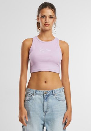 Lavadni kratek top s rebrasto teksturo, na sprednji strani z belim pisanim logotipom; v kombinaciji s svetlo modrimi jeans.