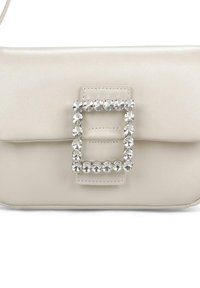 Bolso de cuero crema con un diseño rectangular, que presenta un gran acento de hebilla joya en el frente y una textura suave y elegante.