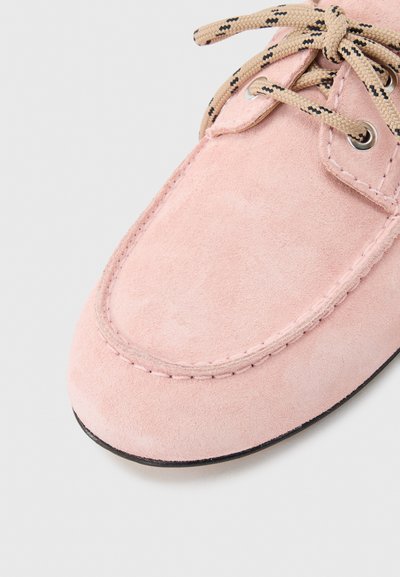 Μαλακό ροζ σουέτ παπούτσι με μπεζ και μαύρα κορδόνια με σχέδιο, μεταλλικές τρύπες και λεπτομερή ραφή σε ανοιχτό φόντο.