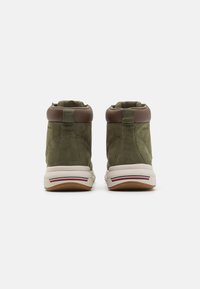 Sneaker high-top verde in suede con dettagli marroni, colletto imbottito e suola in gomma bianca, caratterizzata da una striscia decorativa rossa e blu.