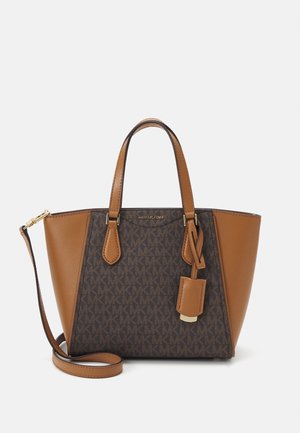 Sac à main en cuir marron et beige avec double poignée, bandoulière réglable et une étiquette de marque suspendue sur le côté avant.