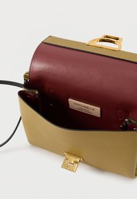 Mala estruturada feita de couro amarelo texturizado com aba em vinho. Apresenta ferragens douradas, fecho magnético e uma etiqueta com marca no interior.