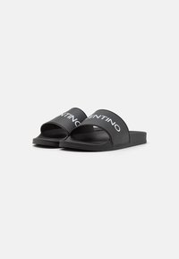 Black slide sandals made of synthetic material featuring a wide strap with 'VALENTINO' logo in white, flat sole, and minimalist design.