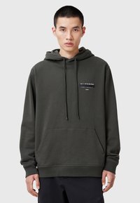 Donkergroene hoodie van zacht materiaal, met een voorzak in kangoeroestijl en een capuchon met trekkoord. Gedrukte merknaam in het wit aan de linkerkant.
