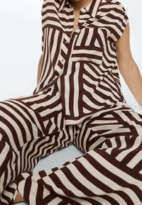 Brown and cream striped shirt and pants set. Short sleeves, button-up shirt with a pocket. Loose-fitting, lightweight fabric with a smooth texture.