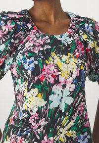 Abito con stampa floreale su sfondo nero, caratterizzato da fiori colorati in rosa, blu, giallo e verde. Maniche a sbuffo e scollo rotondo.