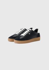Zwarte suède en leren sneakers met witte veters, gumrubberen zool en geperforeerde details. Logo aan de zijkant, gestroomlijnd ontwerp.