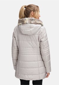 Jasnoszara kurtka typu puffer z kapturem wyłożonym futrem, pikowaną fakturą i długimi rękawami. Posiada pionowe przeszycia na plecach.