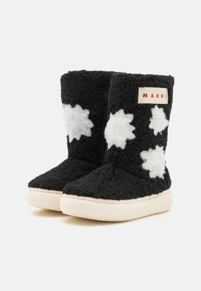 Botas de piel de oveja negras con acentos florales blancos, puntera redonda y suela de goma crema. Etiqueta de marca "MARNI" en rojo en el costado.