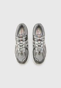 Gray athletic shoes with a breathable mesh upper, white accents, and a textured pattern on the sole. Laces are gray with reflective details.