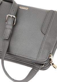 Grauer, strukturierten Lederhandtasche mit einem Reißverschluss und verstellbarem Tragegurt. Verfügt über ein goldfarbenes Hardware-Tag und ein minimalistisches Design.