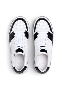 Un paio di sneakers bianche con accenti neri e lacci bianchi, viste dall'alto su uno sfondo bianco.
