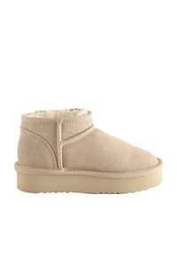 Beige Wildleder-Ankle-Boot mit weichem cremefarbenem Fellfutter, runder Zehenform, dekorativen Nähten und einer flachen Gummisohle mit strukturiertem Grip-Muster.
