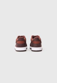 Tenisky Nike s maroon a hnědým koženým svrškem s akcenty z prodyšné látky, bílou mezipodešví a texturovanou hnědou gumovou podešví.