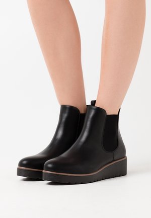 Botas Chelsea de cuero negro con paneles laterales elásticos, puntera cuadrada y una suela baja con plataforma que presenta una banda de rodadura texturizada para mayor agarre.