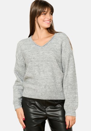 Light gray v-neck sweater with a soft texture, loose fit, and ribbed cuffs, paired with black faux leather pants.