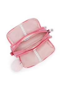 Pink zippered wallet with dual compartments, soft fabric, white accents, and a pink pom-pom attached to the zipper pull.