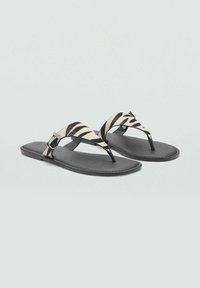 Tasarat mat rata-rata dengan tali kain berpola zebra dan sol karet hitam. Detail gesper yang dapat disesuaikan di salah satu tali.