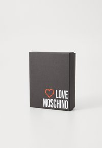 Juodas tekstūruotas dėžutė su lankstomu dangteliu, ant priekinės pusės esantis raudonas širdies ikona ir "LOVE MOSCHINO" baltu tekstu.
