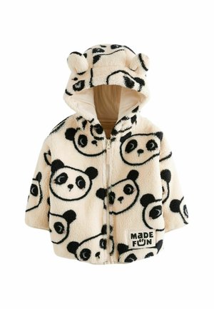 Enfant portant une veste polaire blanche avec des visages de panda noirs, un pantalon noir avec des patchs étoiles et des baskets montantes noires avec des lacets blancs.