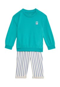 Felpa turchese con collo rotondo e bottoni sulle spalle, abbinata a pantaloni bianchi a righe con linee blu e orli arrotolati.