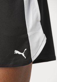 Mustat urheilushortsit, joissa on valkoinen sivupaneeli ja valkoinen Puma-logo vasemmassa alareunassa. Valmistettu sileästä, joustavasta kankaasta.